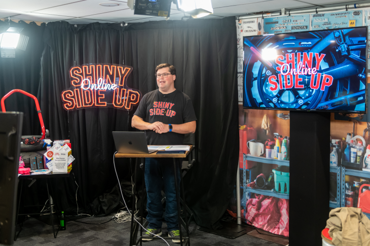 Presenter stands in front of Shiny Side up signage and screens