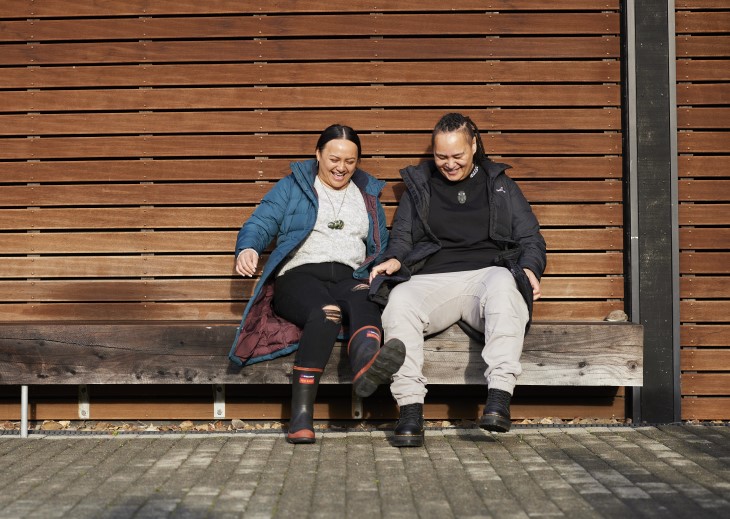 A man and a woman sitting on a bench and laughing together.