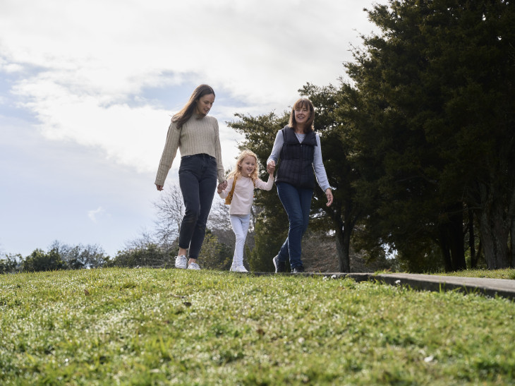 Two women walking in park with a child