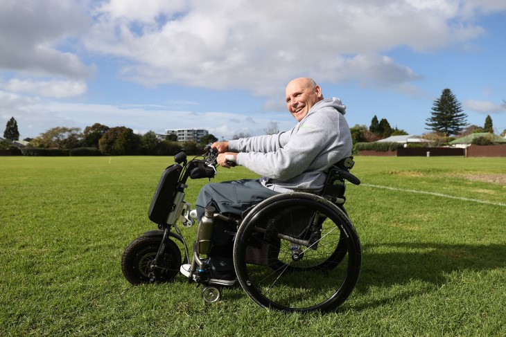Brendan in his wheelchair on a field of grass.