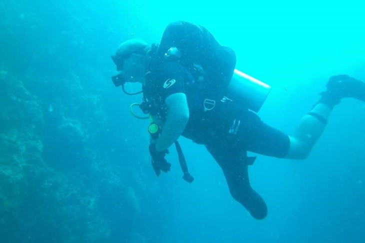 Derek, with his amputated leg in the foreground, dives underwater in scuba gear