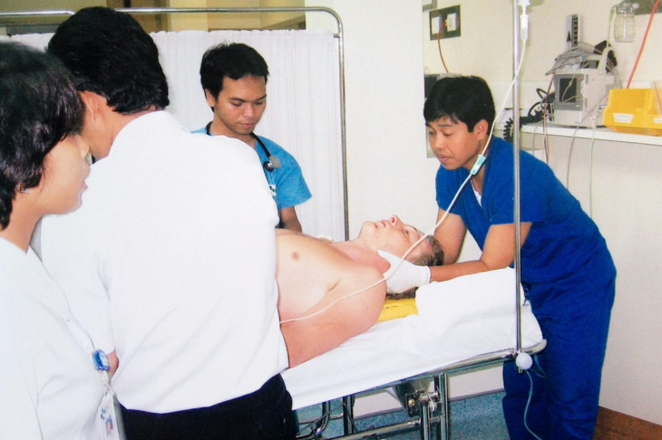 Dr Johnny Bourke lying on a stretcher and being treated by medical staff at a hospital in Singapore