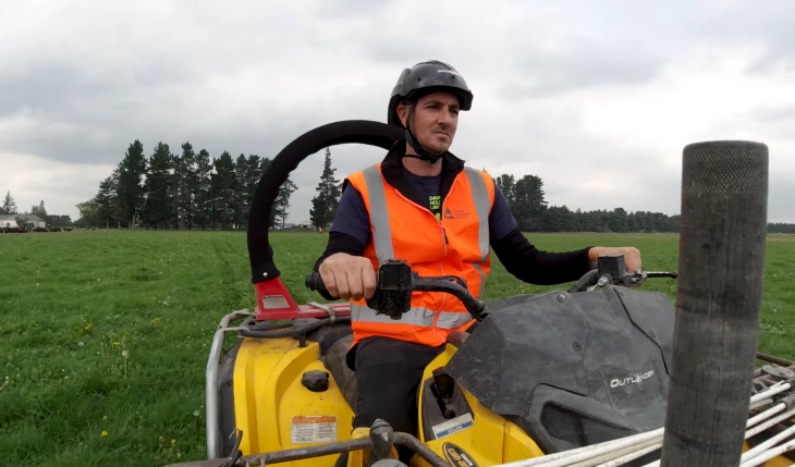 A farmer riding a quad bike with a roll bar.