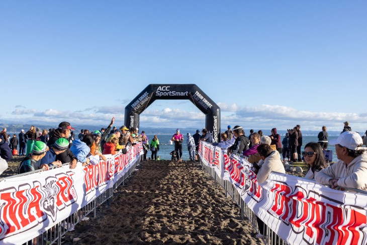 A photo taken on the beach section of the IronMāori course, showing competitors coming out of the wa