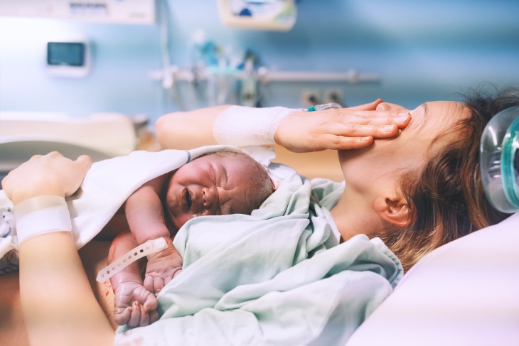 Mother holds her newborn baby on her chest in hospital