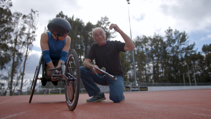 A coach talking to a Para athlete during a training session on the athletics track.