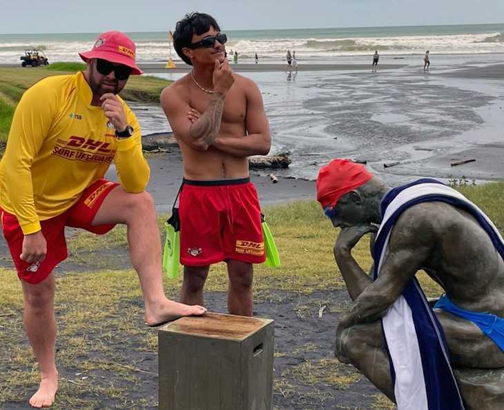 Lifeguards pose with The Thinker at a beach on Auckland's west coast.