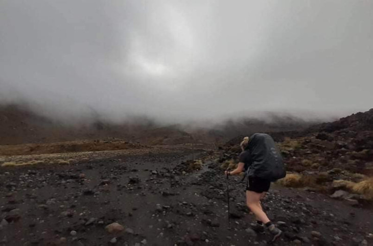 hiker with pack and poles walking on the Tongariro Crossing