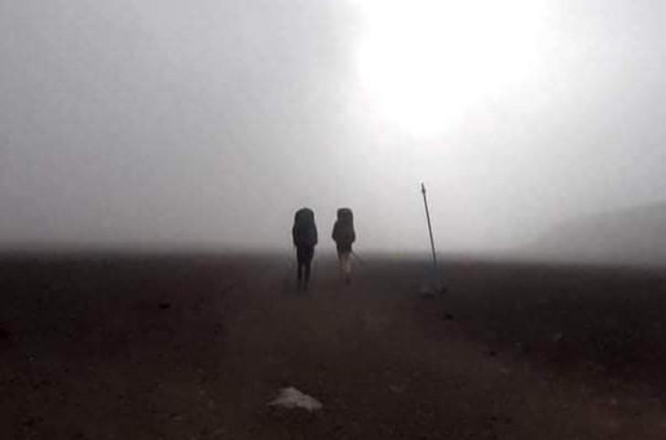 two trampers walking a misty Tongariro Crossing 