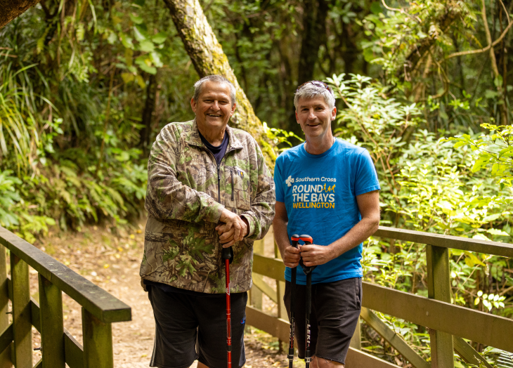 George Thompson and Andrew Leslie standing with their walking sticks on a path in the bush.