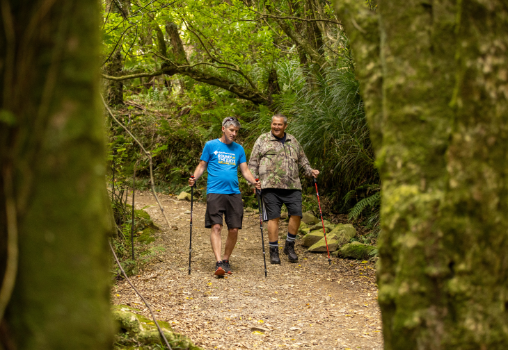 Andrew Leslie and George Thompson using their walking sticks to walk on a path in the bush. 
