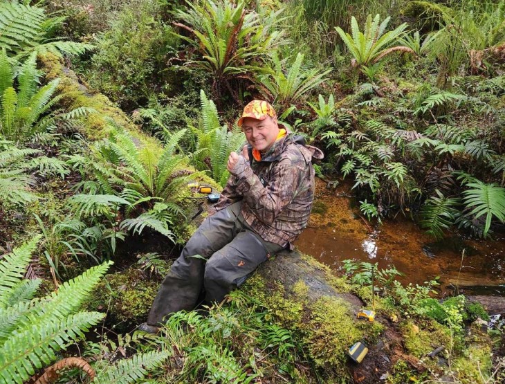 Andy Pedley sitting on a log in the bush after breaking his leg. 