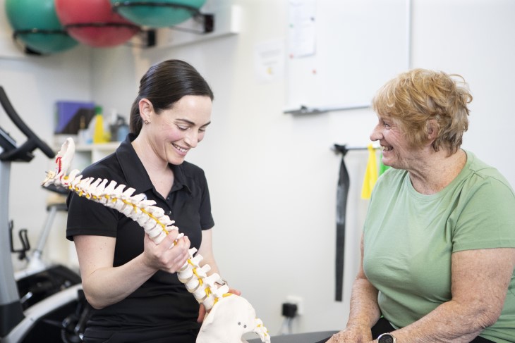 A young female physio talking to an older woman during a consultation.