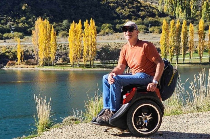 Ben Lucas sitting in his wheelchair in front of a lake.