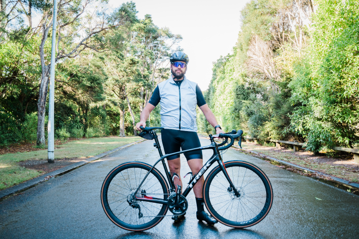 Blake Jones standing on the road with his road cycling bike.