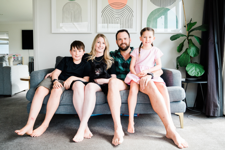 Blake Jones sitting on a couch with his wife and two children in their living room.