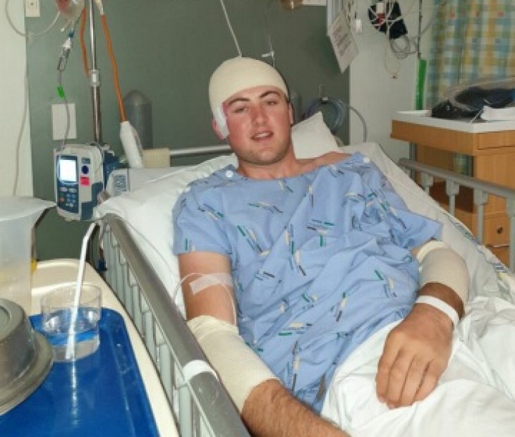 Campbell Gray lying in a hospital bed with a bandage around his head.