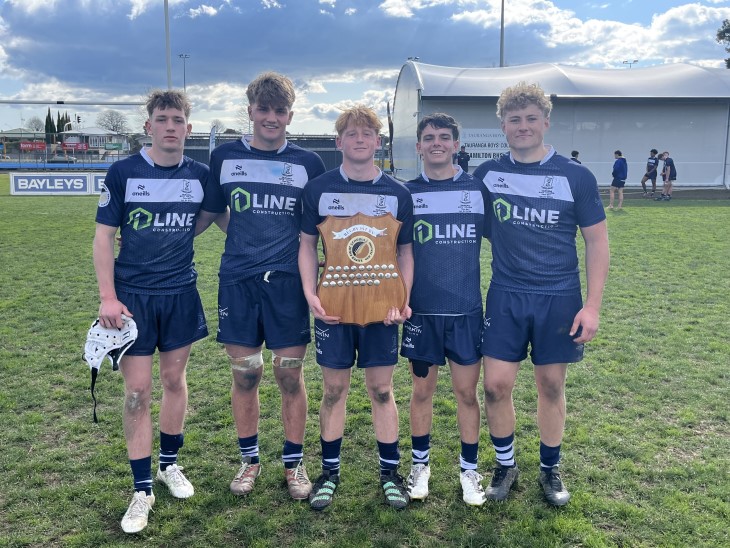 Charlie Sinton standing with four of his school teammates and holding a shield.