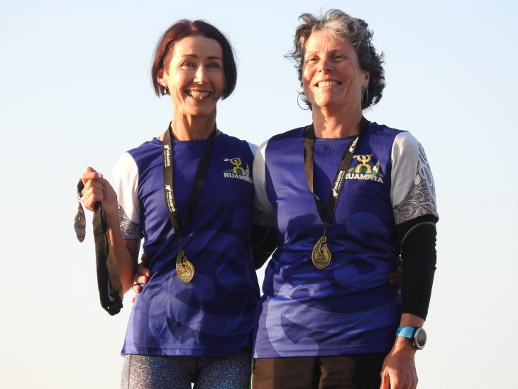 Christina Stockman standing next to a fellow waka ama female team member, both are wearing medals around their neck.