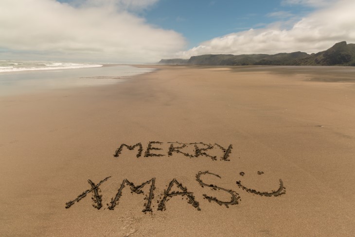 A message saying 'Merry Xmas' written in the sand on a beach. 
