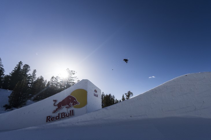 A long-range photo of Cool Wakushima doing a snowboard jump.