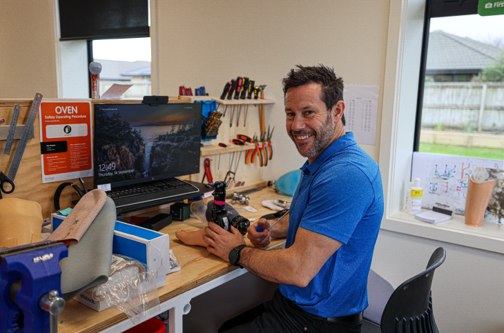 Craig Harrington sitting at his work desk and smiling at the camera. 