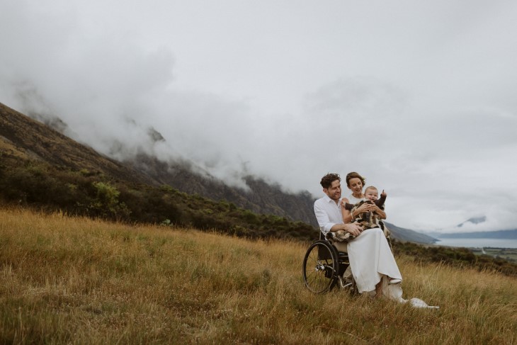 Dan Buckingham with wife Samantha and daughter Etta on their wedding day, in front of a misty mountain.