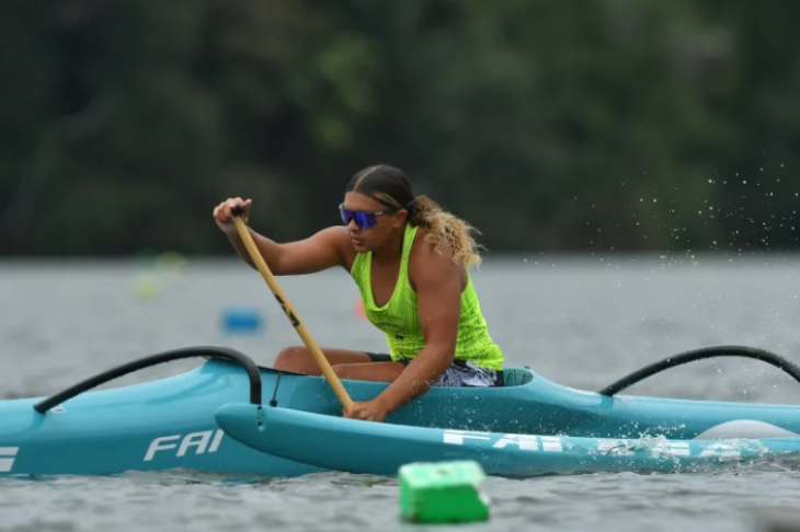 Hine Brooking paddling in her waka ama canoe on the water.