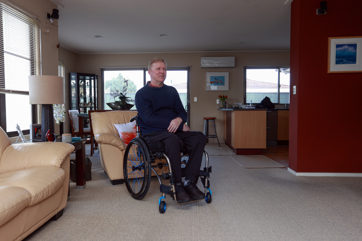 Jason Ross sitting in his wheelchair in the lounge of his home.