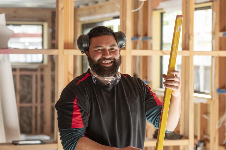 A builder standing on a home construction site and smiling.