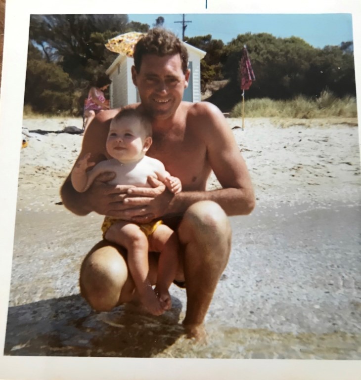 Megan Main as a young child being held by her dad at the beach. 