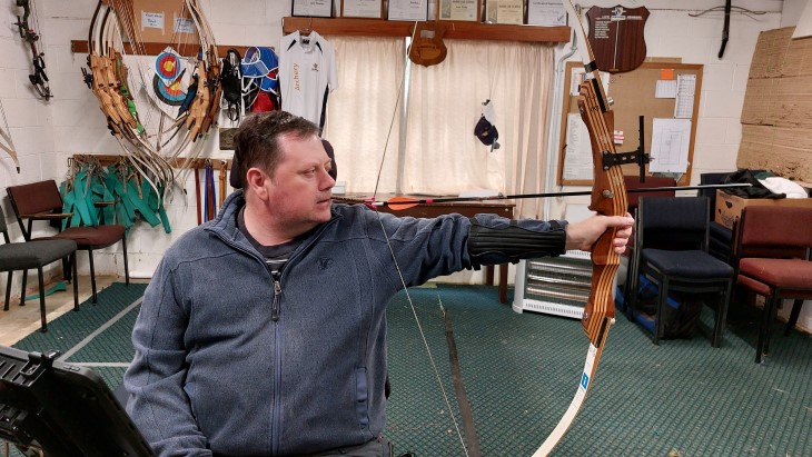 Paul Wallace using his bow to shoot an arrow.