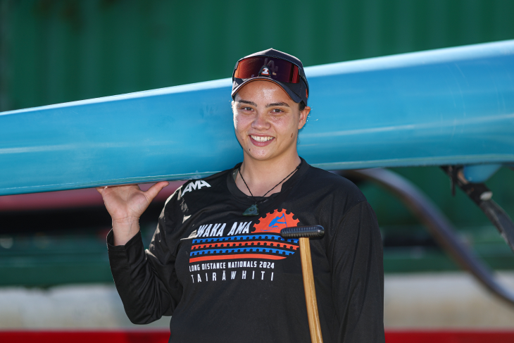 A close-up photo of Peata Nuku holding her waka ama canoe and smiling.