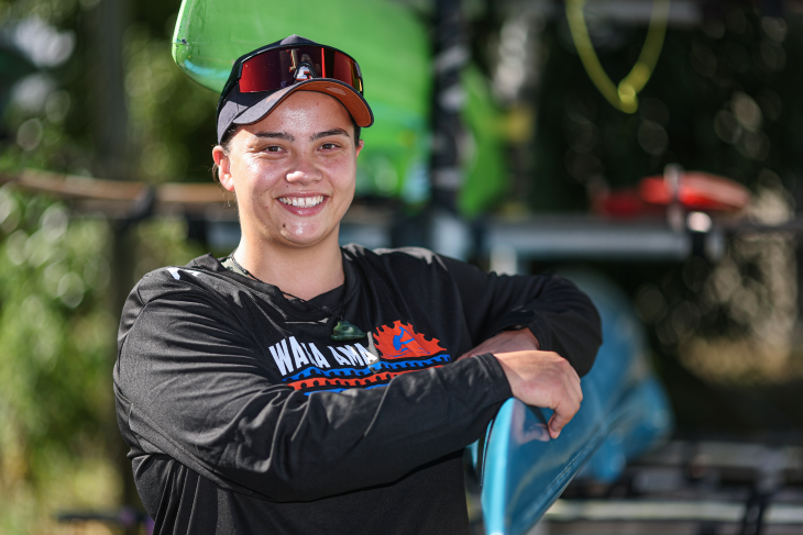 Peata Nuku leaning on her waka ama canoe and smiling.