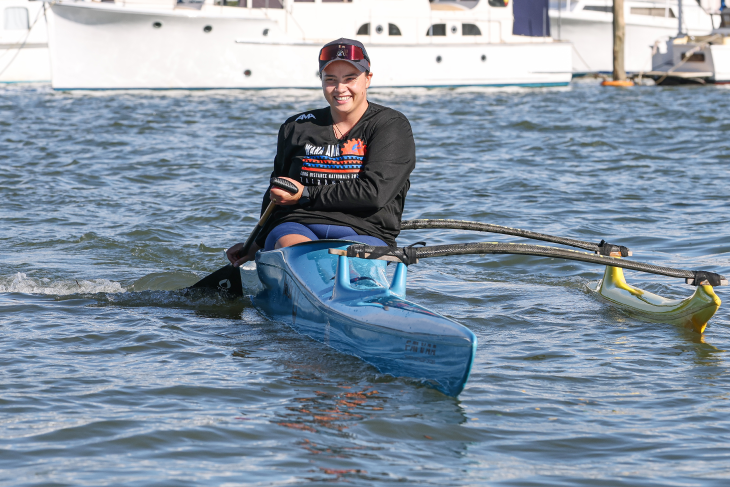 Peata Nuku paddling in her waka ama canoe on the water.