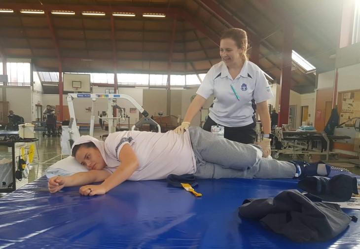 Peata Nuku lying on a table and being treated by a healthcare professional at the Auckland Spinal Unit.