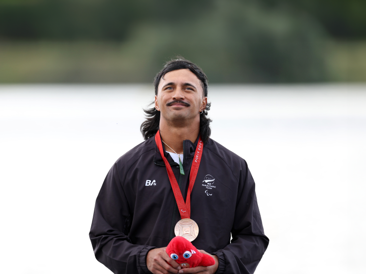 Peter Cowan on the podium at the Paralympics with his medal around his neck.