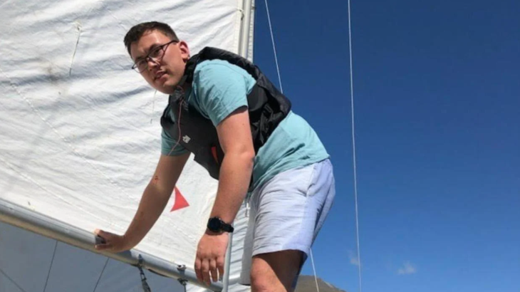 Sean Dickey standing on a boat and leaning on the bottom of the sail.