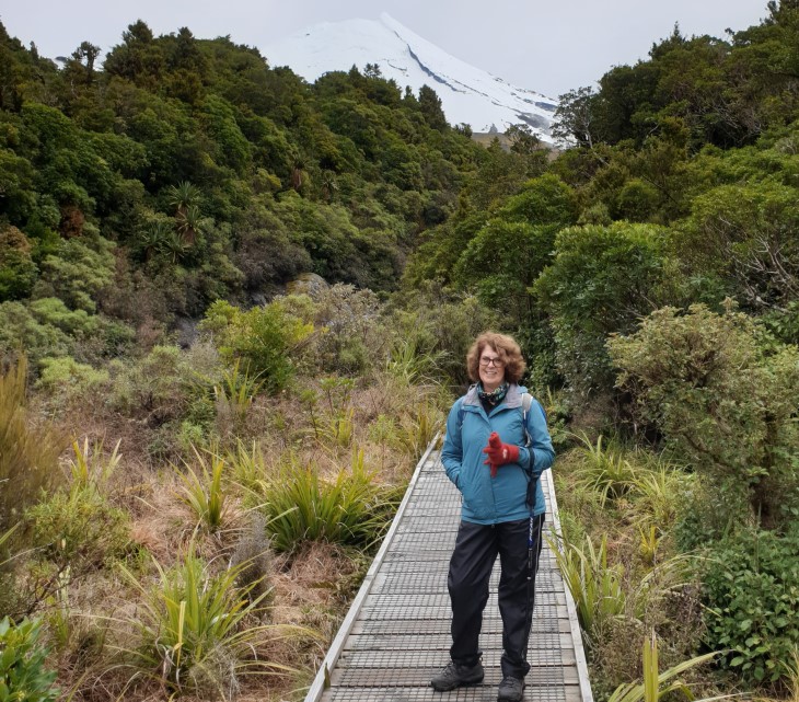 Sharleen Bishop standing on a path in the bush with Mount Taranaki in the background.