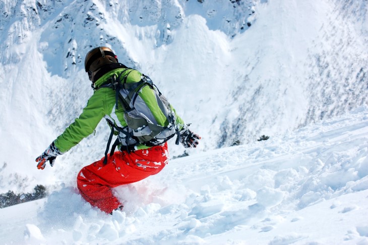 A woman shown snowboarding down a mountain from behind.