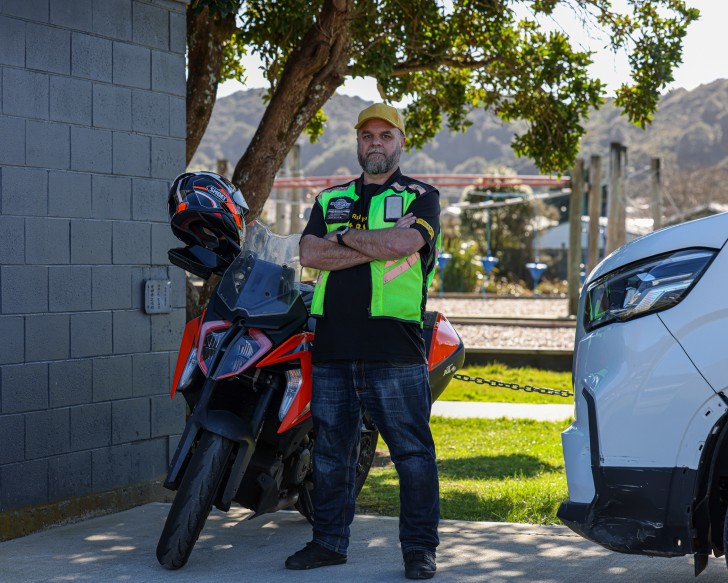 Steve Davies standing next to his motorbike with his arms folded.