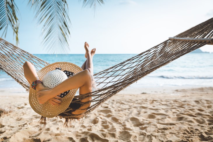 A woman relaxing in a hammock on the beach. 