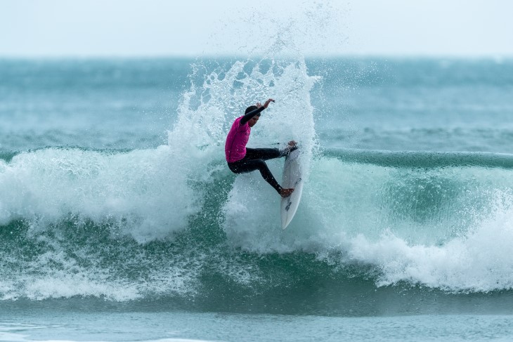 A male surfer riding the crest of a wave.