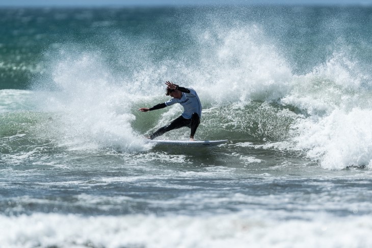 A male surfer riding the foot of a wave.