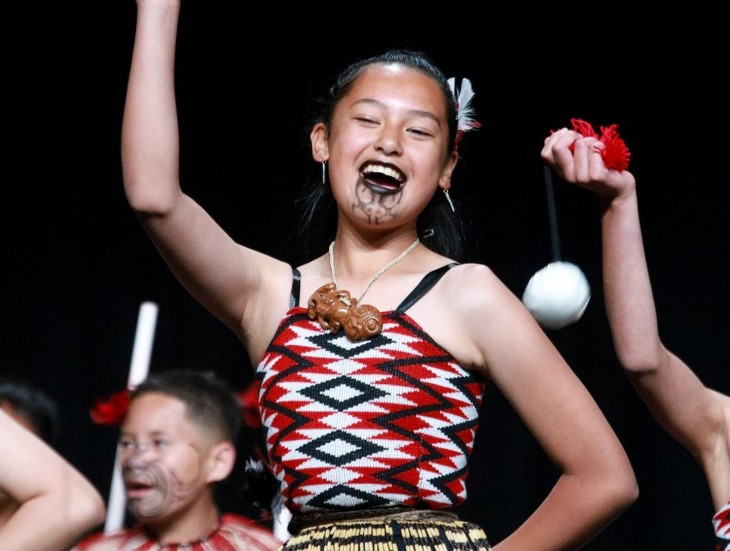 A young woman wearing traditional Māori clothing performing in a kapa haka group.