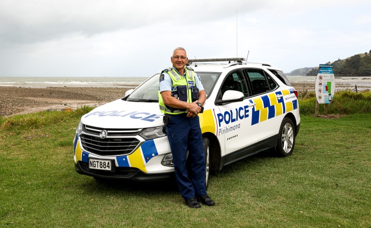 Senior sergeant Tony Mumford leaning on his police car. 